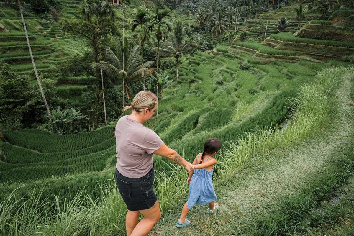 Visitors walking a rice terrace path in Bali